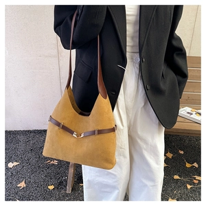 Detail of suede bucket bag in mustard yellow with dark brown strap on a model