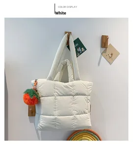 Detailansicht der weißen gesteppten Puffer-Tasche mit buntem Plüsch-Fruchtanhänger