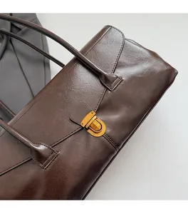 Close-up of a dark brown vintage handbag featuring a polished gold square metal buckle