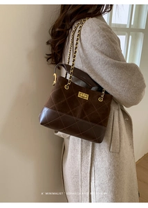 Close-up of brown quilted suede bucket bag with gold chain strap and turn-lock closure