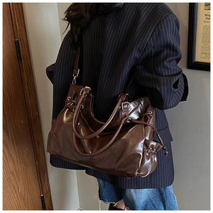 Detail view of brown glossy oil leather tote with soft drawstring and pleated side styling