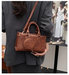 Close-up of retro brown textured handbag with gold hardware and a small round coin purse