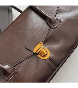 Detailed view of the vintage gold metal buckle and stitching on a brown leather bag