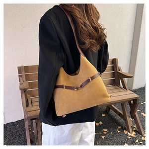 Close-up of vintage brown suede hobo bag with leather strap and metal buckle detail