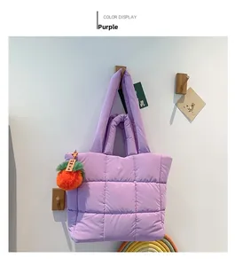 Detail der lila gesteppten Nylon-Einkaufstasche mit dekorativem orangefarbenem Plüschanhänger
