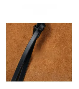 Close-up of black leather strap knot against premium brown suede texture of a shoulder bag