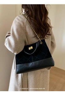 Quilted bucket bag with chain strap and gold hardware worn by a model in beige coat