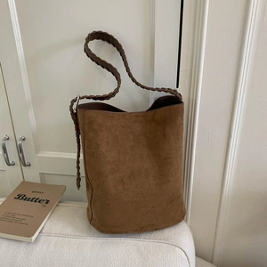 Detail of woven strap on brown suede hobo bag against a minimalist home background