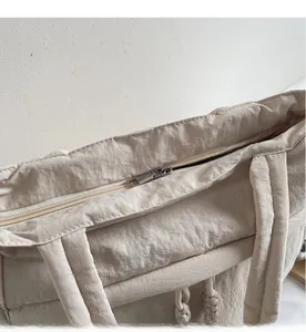 Detailaufnahme des glatten Metallreißverschlusses und der Steppung dieser beigen Tasche