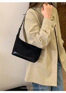 Detail of retro black underarm bag with matte suede texture on model in beige jacket