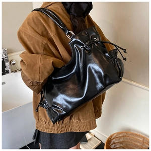 Detail of glossy black leather tote bag showing large capacity and soft texture on shoulder