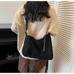 Detail of black suede hobo bag with adjustable leather strap and silver buckle