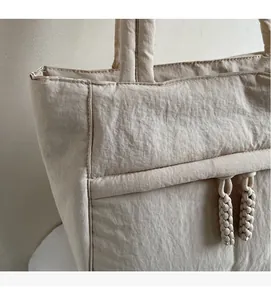 Detail einer beigen Oxford-Tasche mit weicher Faltenstruktur und Kordelverzierung