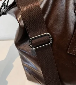 Dettaglio della tracolla marrone regolabile con fibbia in metallo su borsa tote