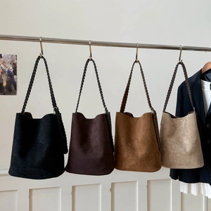 Close-up of suede bucket bags in four colors with decorative woven shoulder straps