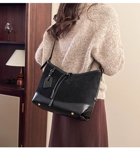 Detail of black suede tote bag with leather trim and gold protective metal feet