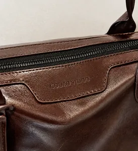 Dettaglio macro della borsa tote in pelle marrone scuro con texture e logo inciso
