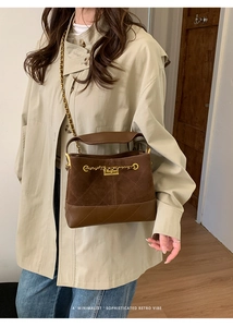 Model wearing a dark brown quilted bucket bag with chain strap in a retro interior setting