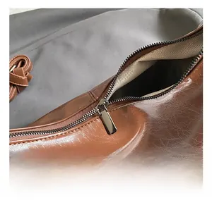 Detailed close-up of premium metal zipper and woven lining on a vintage brown leather bag