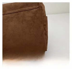 Détail macro du daim marron montrant des coutures fines sur un sac à bandoulière vintage