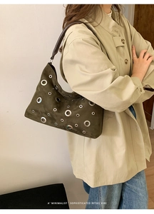 Detailed shot of an olive green suede shoulder bag with retro silver metal eyelet accents