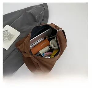 Vue de dessus d'un grand sac en daim marron montrant l'intérieur spacieux avec ordinateur