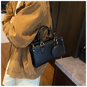 Detail of black leather handbag with round coin purse and elegant golden hardware