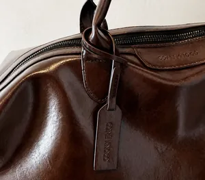 Dettaglio delle cuciture e dell'etichetta di questa borsa da viaggio in pelle marrone