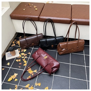 Four retro shoulder bags in black, brown and burgundy on a bench with autumn leaves