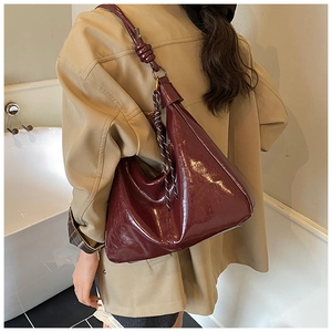 Close-up of deep wine red patent leather tote with a knot shoulder strap and striped charm
