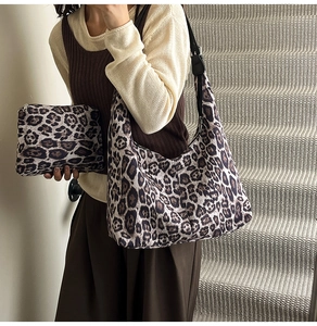 Detail view of leopard print tote and pouch set styled on shoulder in a cozy indoor setting