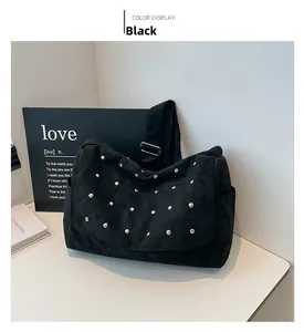 Détail du sac à bandoulière noir avec rivets argentés et large sangle réglable