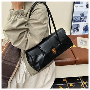 Detail of black underarm bag with vintage pleated texture and gold rotating buckle