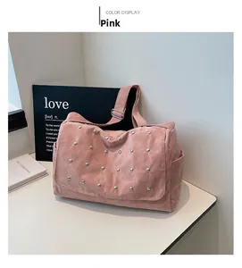 Détail d'un sac à bandoulière en daim rose orné de rivets argentés et poches latérales