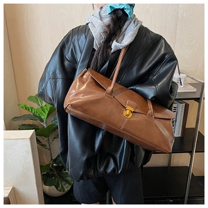 Side view of a brown leather shoulder bag with vintage gold metal buckle on a model