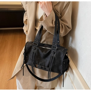 Dettaglio della borsa punk vintage nera con lacci incrociati su trench color kaki