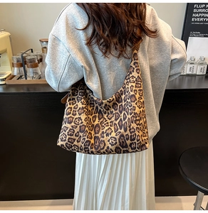 Fashionable leopard print hobo bag worn on shoulder in a cozy cafe setting