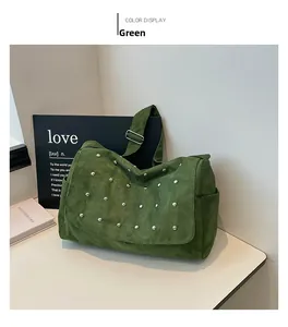 Gros plan du sac bandoulière en daim vert avec rivets argentés et sangle réglable