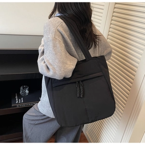 Detail einer großen schwarzen Tragetasche am Modell, die den Schulter-Look für den Alltag zeigt