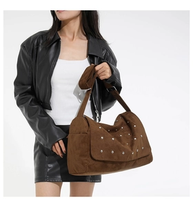 Gros plan sur un sac porté épaule en daim marron avec des détails de rivets métalliques