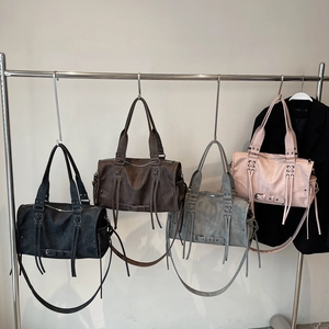 Retro motorcycle handbags with tassels and rivets in four colors on a display rack