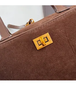 Detailed close-up of brown suede handbag featuring a premium golden metal turn-lock closure
