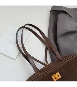 Detail of premium brown suede tote with golden metal clasp and reinforced leather strap