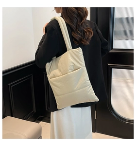 Quilted tote bag with padded nylon texture and long shoulder strap on model back view