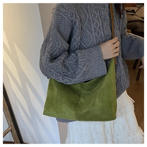 Détail du sac hobo en daim vert avec sa bandoulière fine en cuir marron foncé