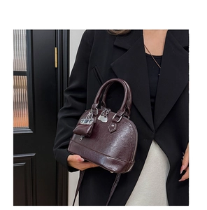 Détail du sac à main marron foncé avec texture cuir et pendentif mini porte-monnaie