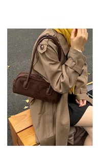 Close-up of vintage brown suede baguette bag with leather strap on a model shoulder