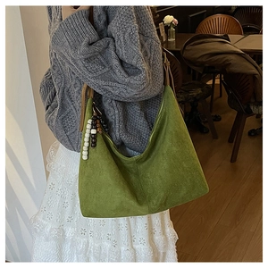 Detail of green suede hobo bag with colorful beaded charm and adjustable strap