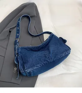 Detail of blue denim hobo bag featuring side flap pockets and adjustable metal buckle strap