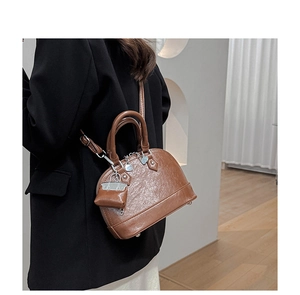 Sac vintage marron en forme de coquille avec double poignée porté par un mannequin en studio